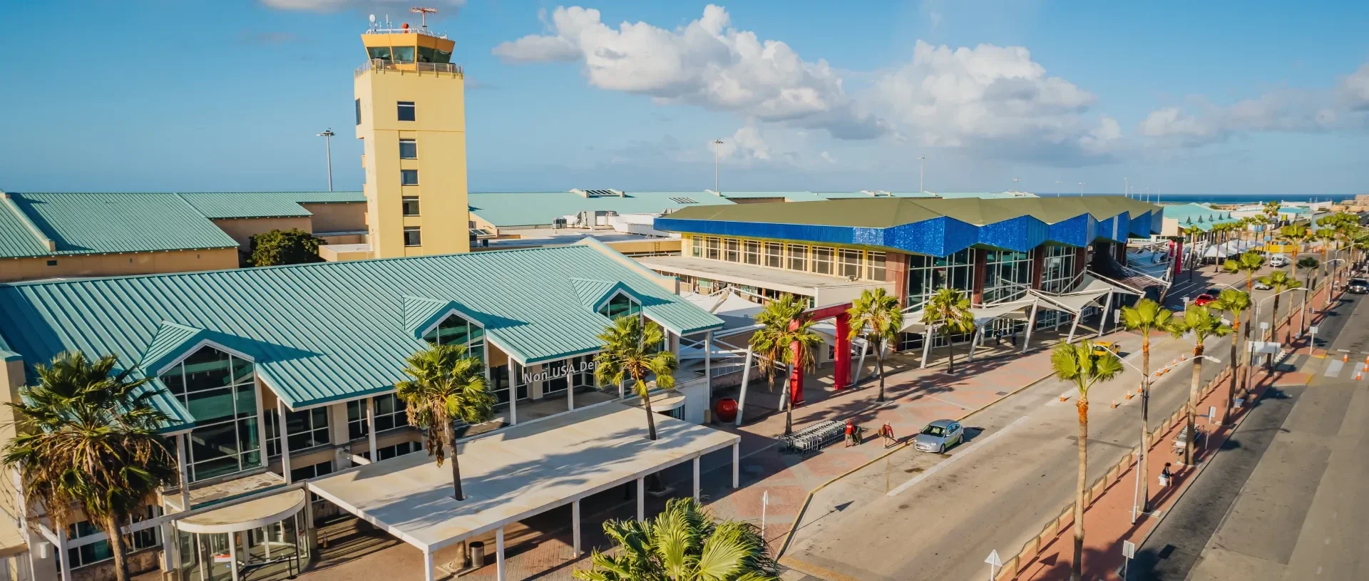 Aerial view of Aruba Airport terminal, control tower and Non-USA Departures hall beneath a Caribbean sky