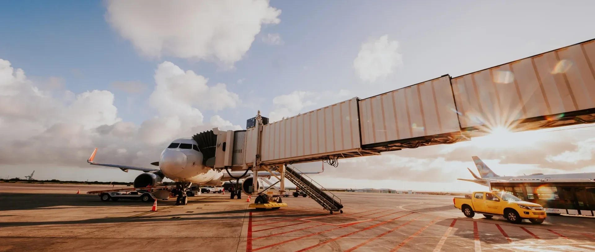 Aircraft at gate connected to jet bridge with ground service vehicles on the apron